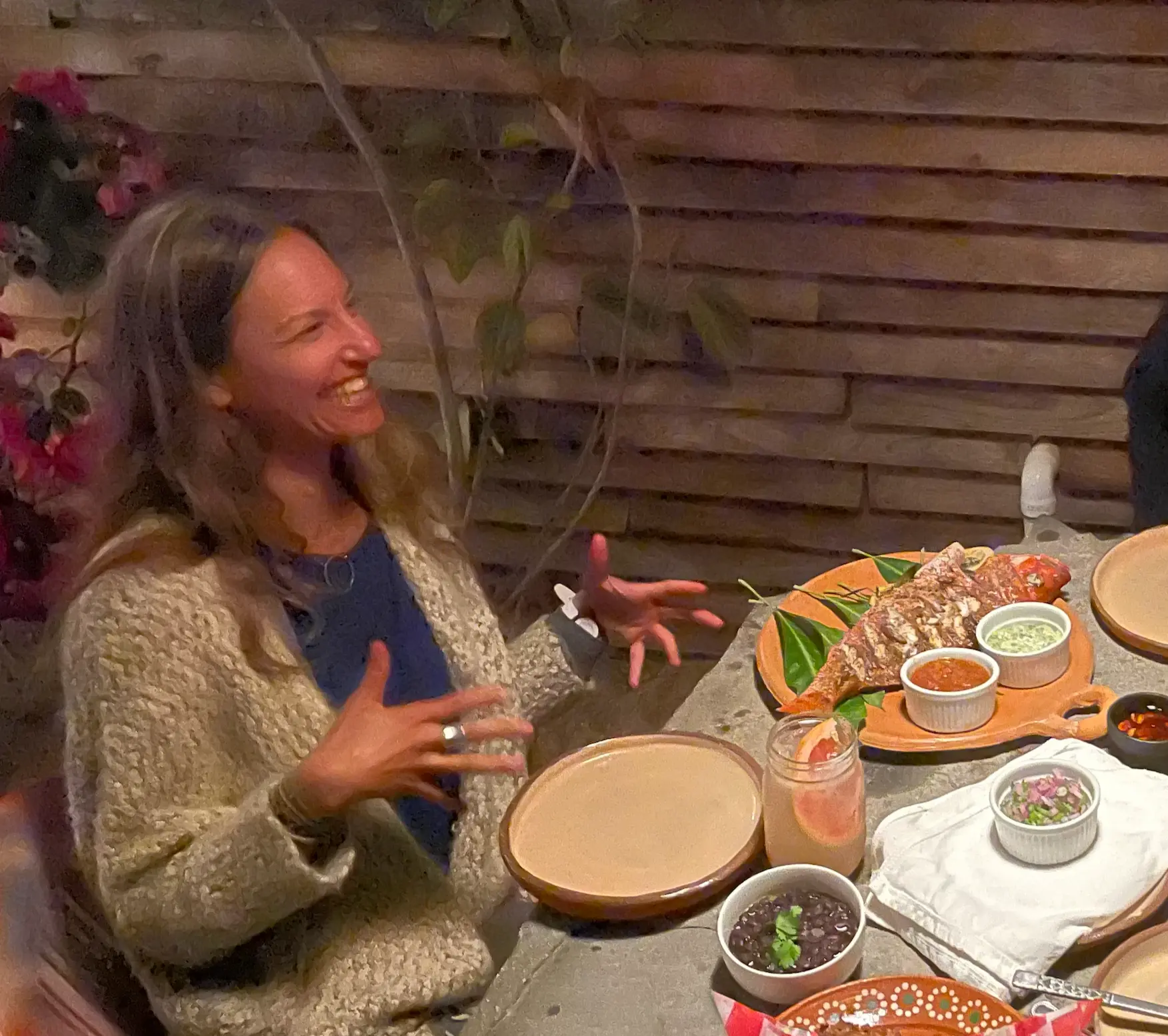 Lisa Kalfus laughing mid conversation at a candlelit dinner table