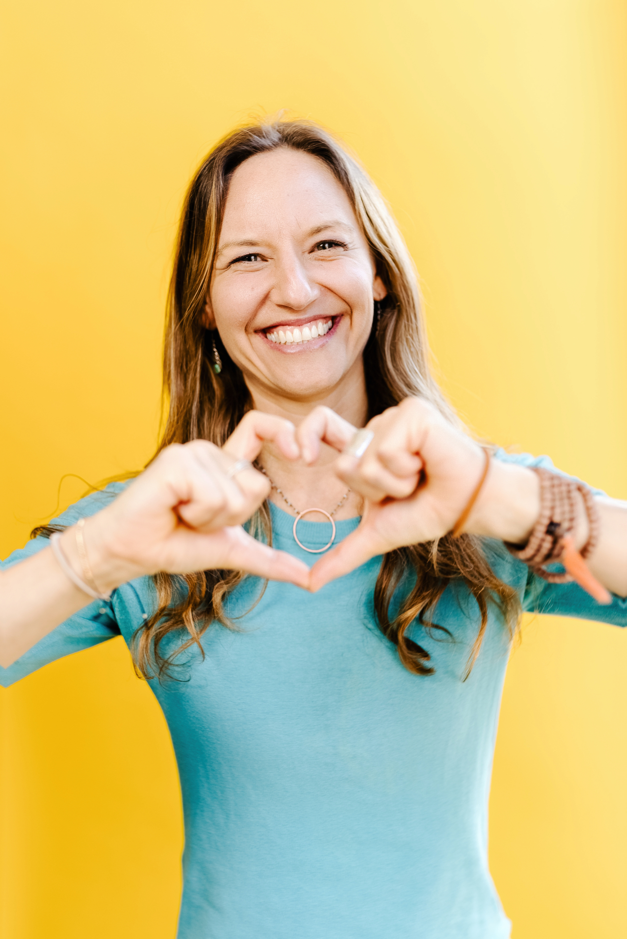 Lisa Kalfus making a heart with her hands against a warm backdrop