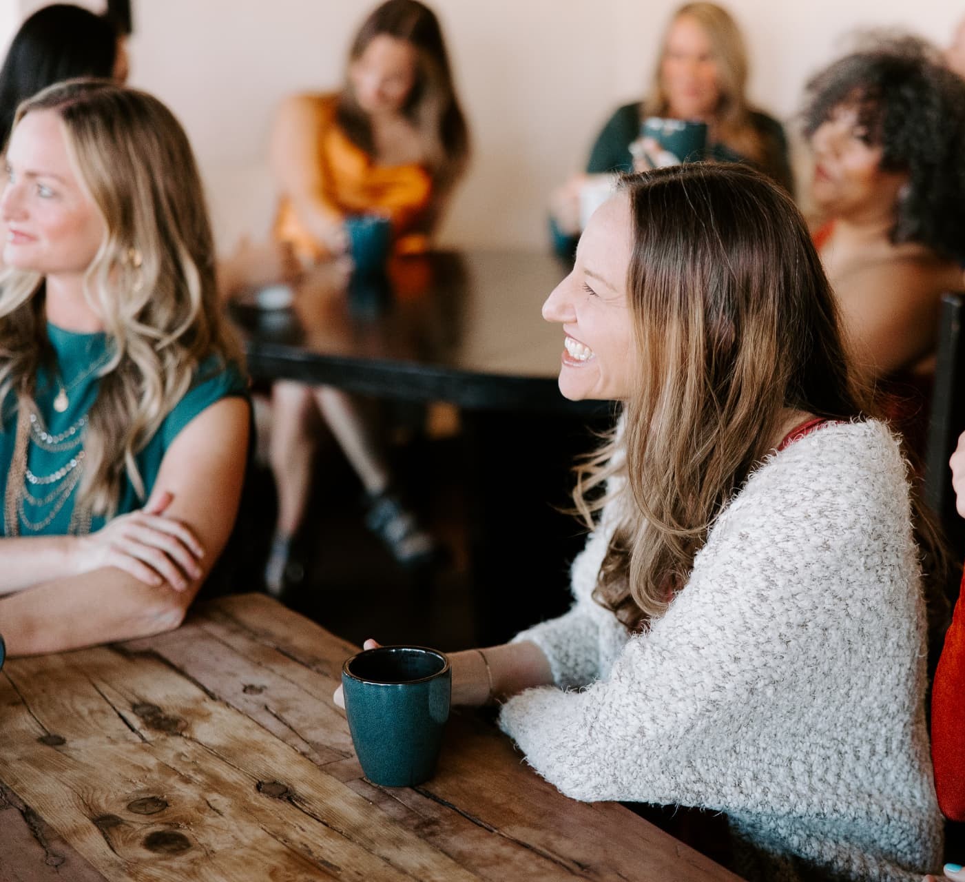 Women in warm conversation around a wooden table over coffee
